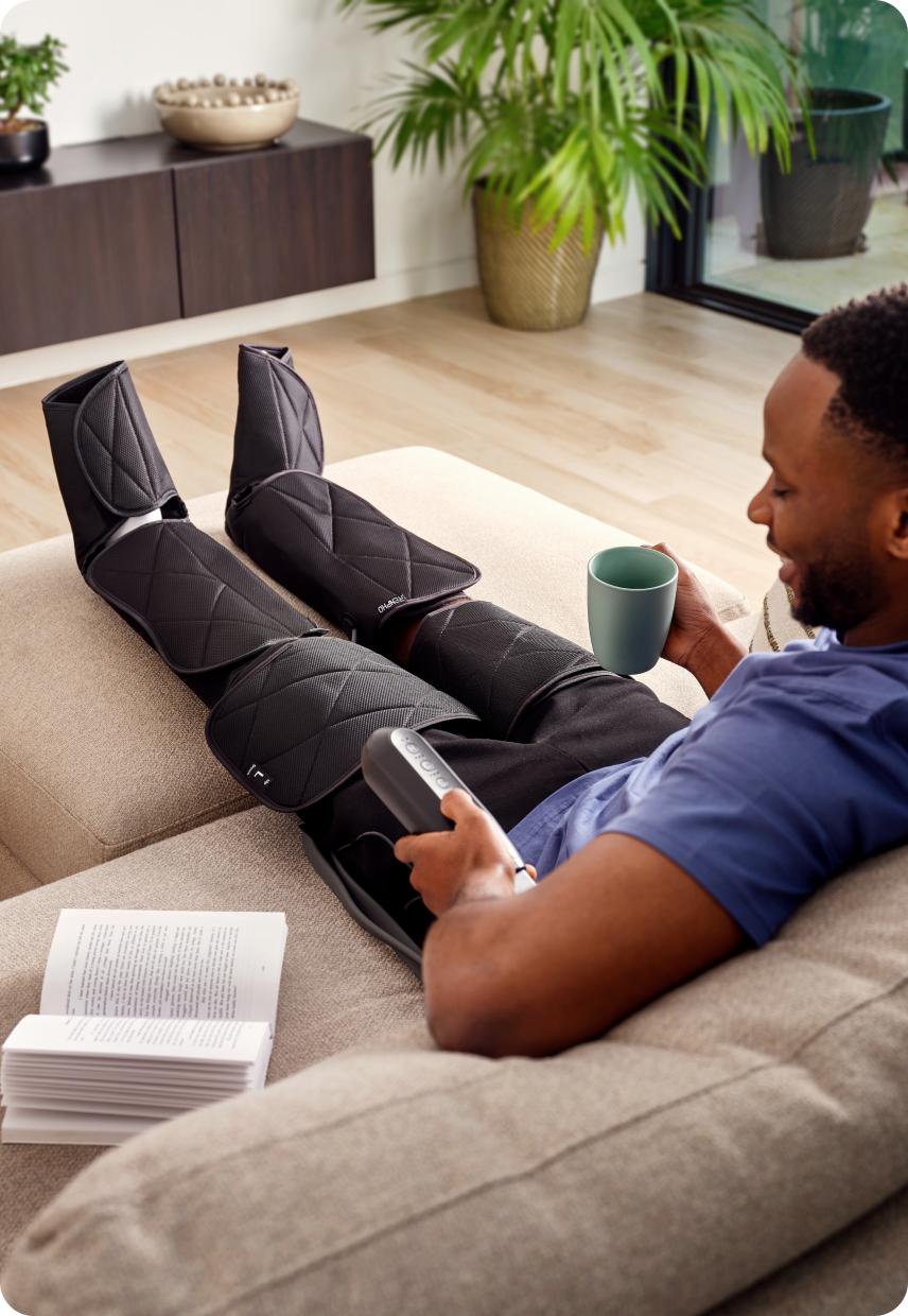 A man on a sofa with massagers on his legs