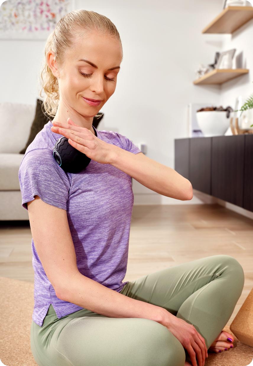 A lady wearing activewear, using a roller on her shoulder
