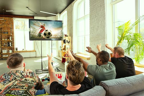 a group of people sitting on a couch watching a soccer game