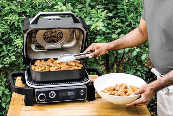 a man is cooking food in a ninja woodfire grill