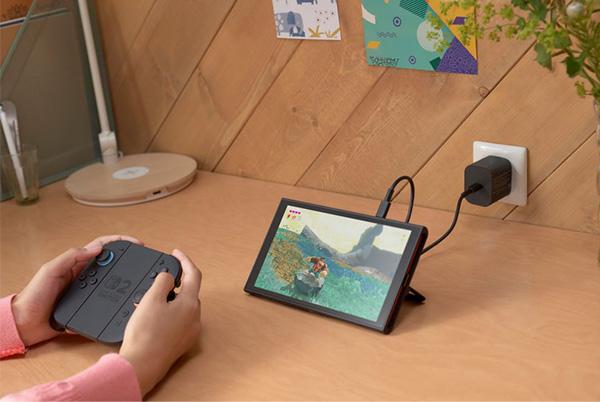 a person playing a nintendo switch 2 on a wooden table with the charger plugged in