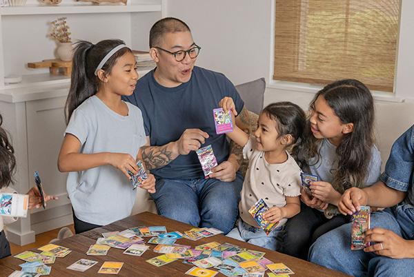 a family sitting around a table playing the pokemon trading card game