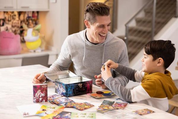 a father and son playing with pokemon cards in a living room
