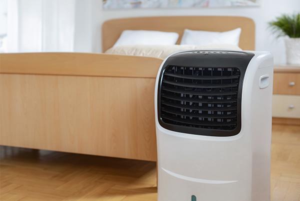 a small air conditioner sitting on a wooden floor in a bedroom