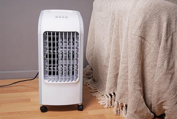 a white air conditioner sitting on a wooden floor next to a blanket