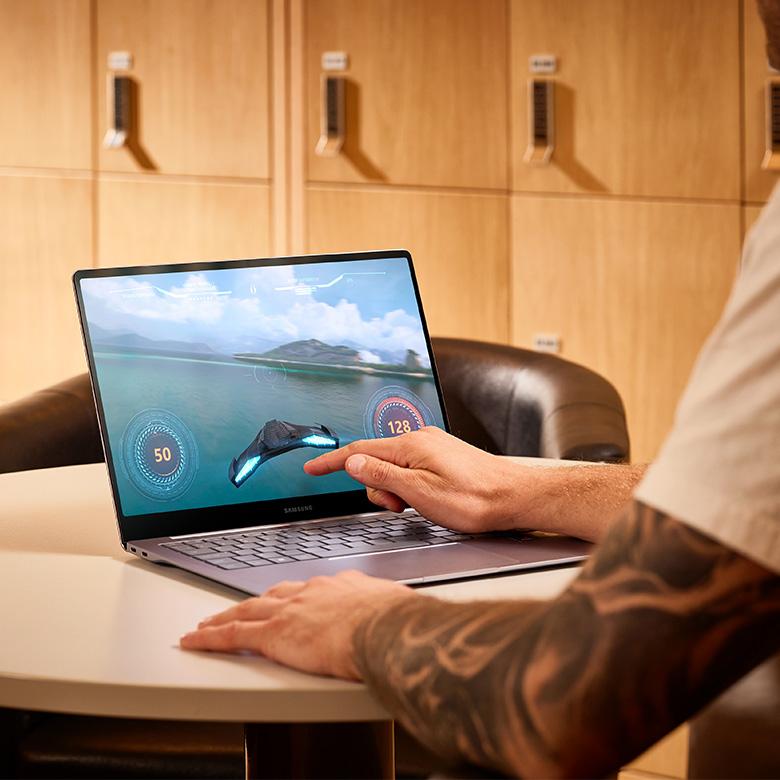a man with a tattoo on his arm is using a laptop for gaming