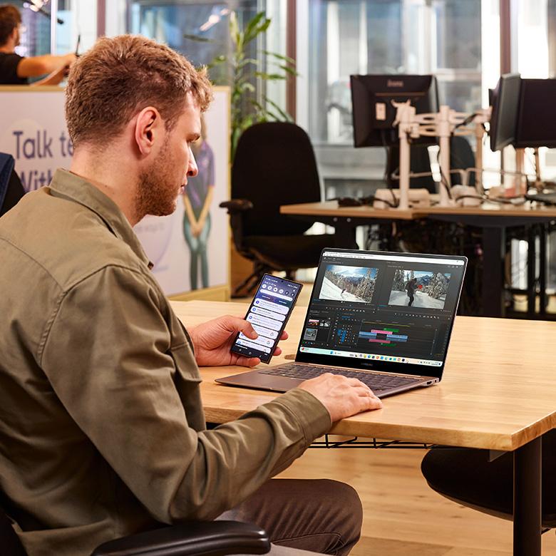 a man sitting at a desk with a laptop and a phone