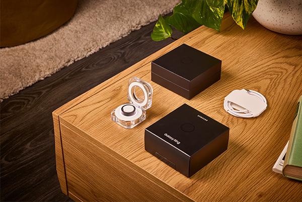 samsung galaxy ring in its charging case next to packaging on a wooden coffee table