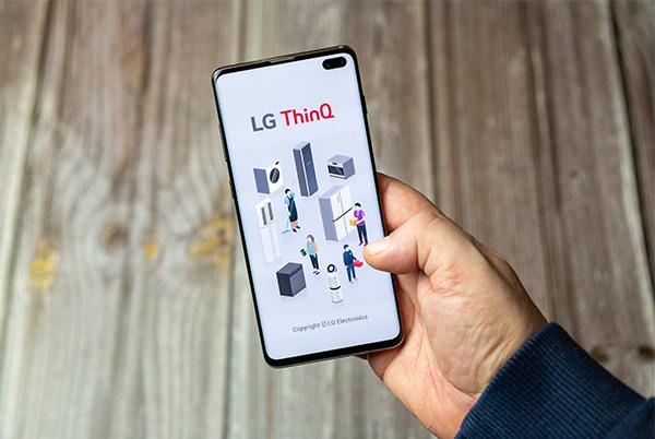 a person holding a mobile phone with a screen displaying lg thinq app