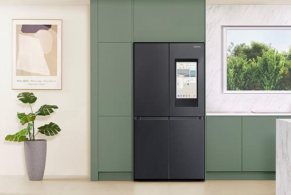 a black refrigerator in a green kitchen with a green plant