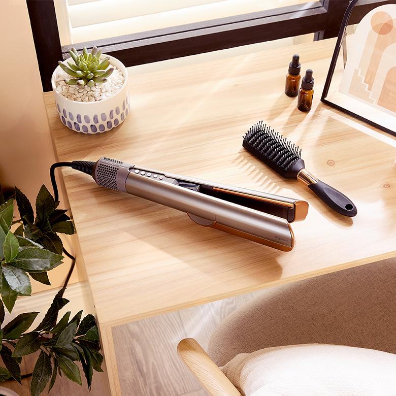 dyson airstrait hair straightener on desk with hair brush