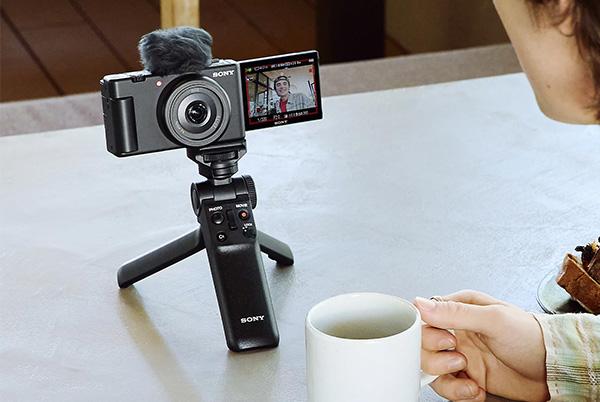 a person sitting at a table with a cup of coffee and a video camera