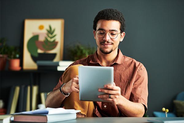 a man sitting at a table with a tablet computer