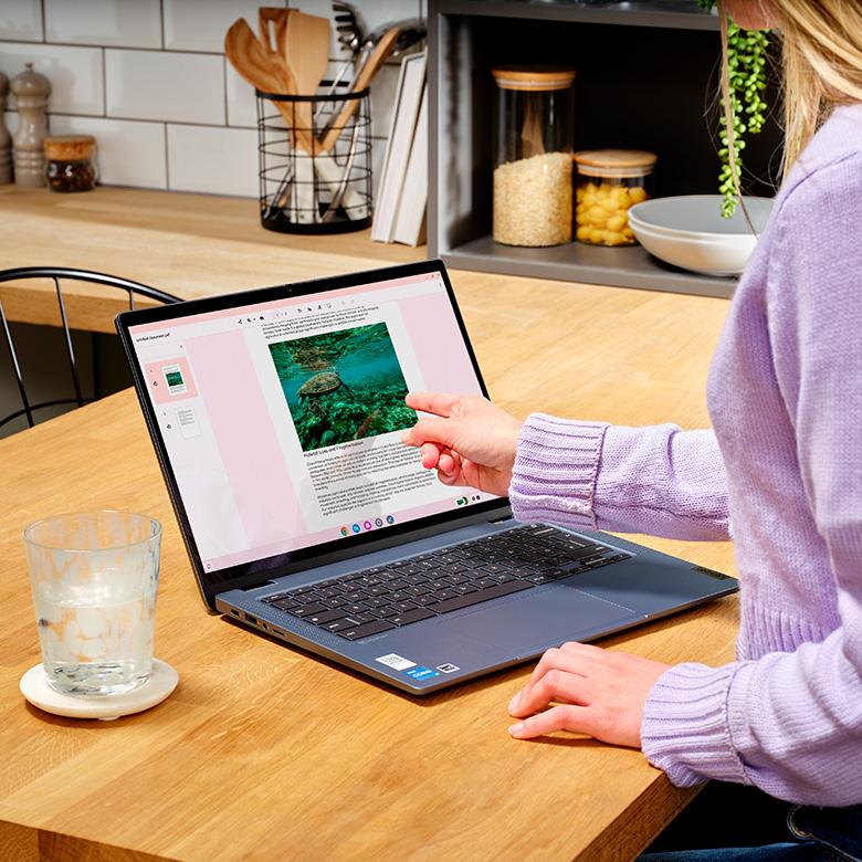 person pointing finger at lenovo ideapad flex 5 laptop screen while using it on a desk