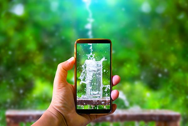 a person holding a mobile phone in front of a green background