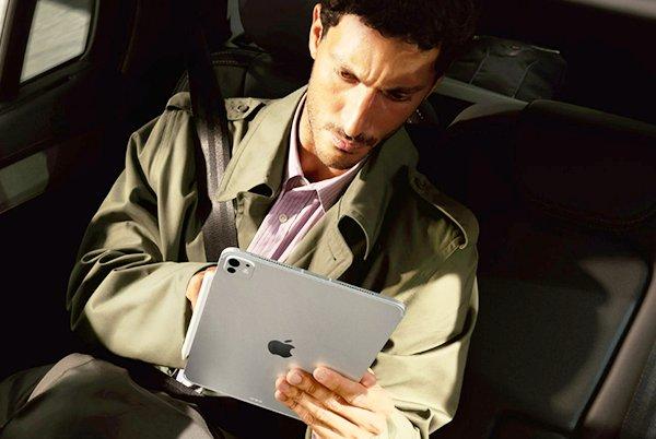 a man sitting in a car with an ipad in his lap