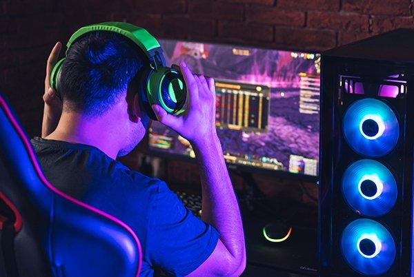 a man wearing headphones playing a video game in front of a computer