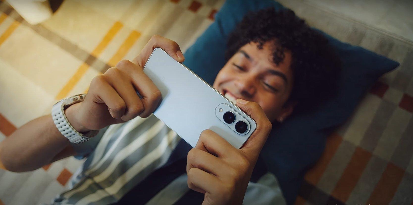 a man laying on a bed holding a Samsung Galaxy S25 Edge phone