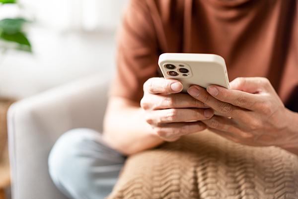 a person sitting on a couch holding a mobile phone