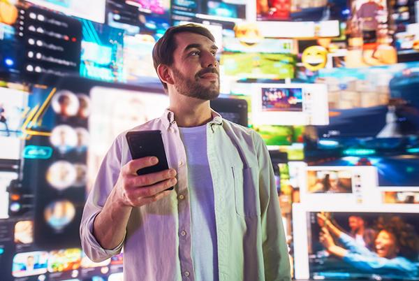 a man standing in front of a wall of screens holding a cell phone