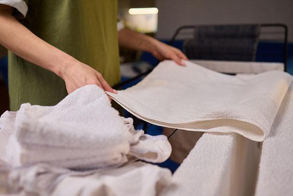 a person folding a white towel on a heated airer