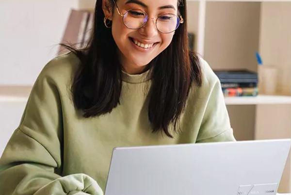 a woman in glasses smiling while using an Asos Vivobook