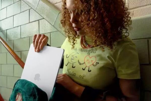 a woman sitting on a step holding a Macbook