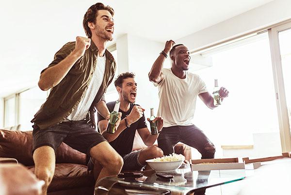 three men are playing a video game in a living room