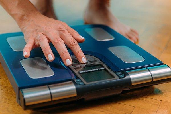 a woman's hand on a blue electronic scale with a digital display