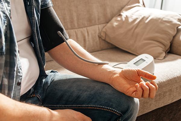 a man sitting on a couch with a blood pressure monitor