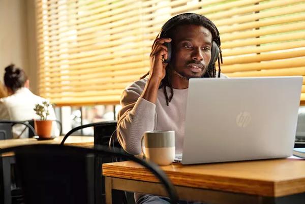 a man sitting at a table with a laptop and headphones