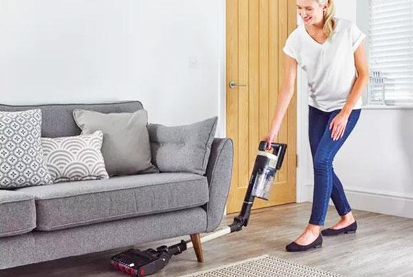 woman using a vacuum cleaner to clean a couch