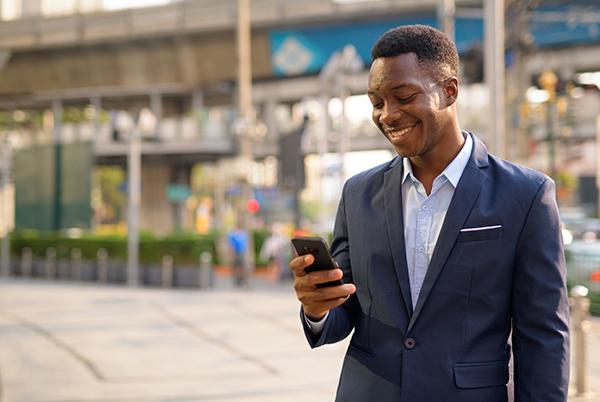 a man in a suit looking at his phone on the street