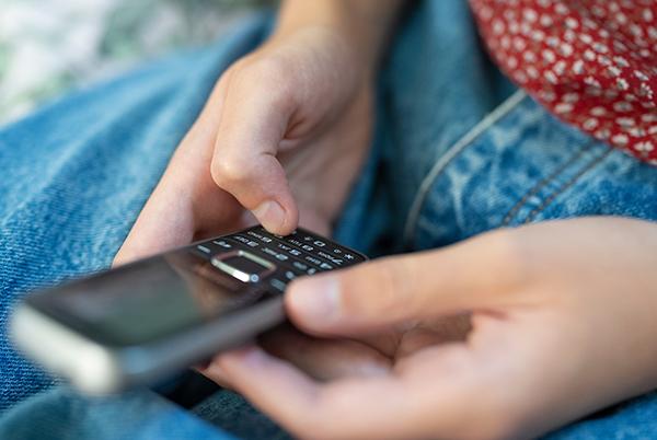 a person holding a non-smartphone in their hand while sitting on a couch