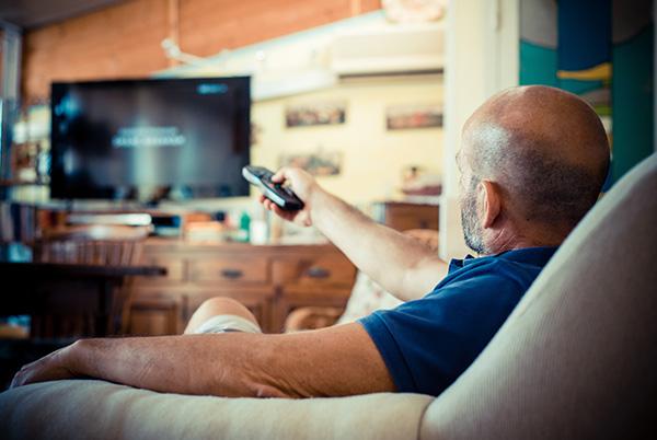 a man sitting on a couch with a remote control in his hand
