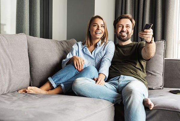 a man and woman sitting on a couch watching TV