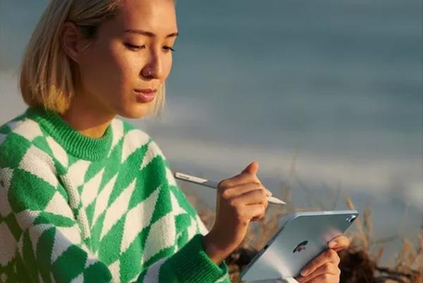 a woman sitting on a beach with an ipad mini