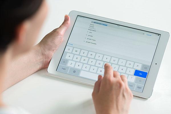 A woman typing on an onscreen iPad keyboard.