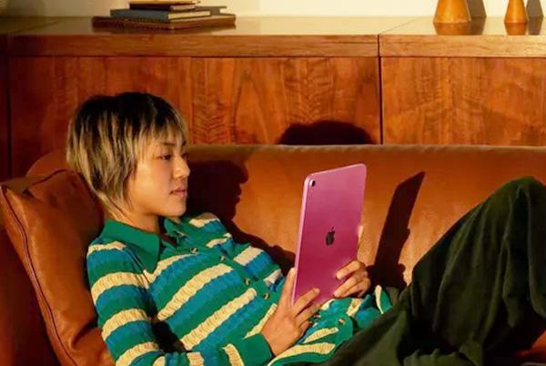 a woman laying on a couch with a pink ipad