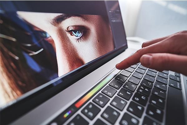 a person typing on a laptop with a picture of a woman on the screen
