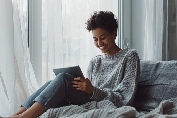 a woman sitting on a bed with a tablet in her lap