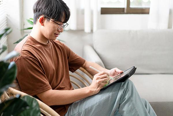 a man sitting in a chair with a tablet and pen