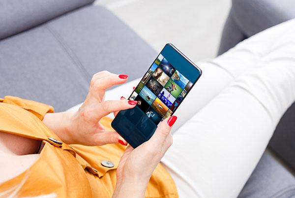 A woman sitting on a couch holding a mobile phone