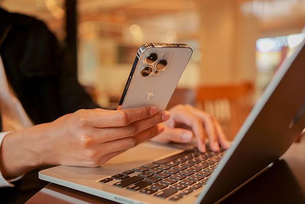 a person sitting at a table with a laptop and a mobile phone