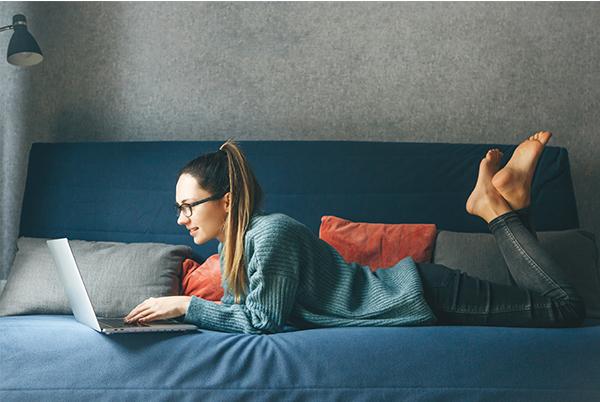 a woman laying on a bed with a laptop on her lap
