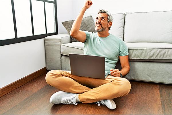 a man sitting on the floor with a laptop in his hand