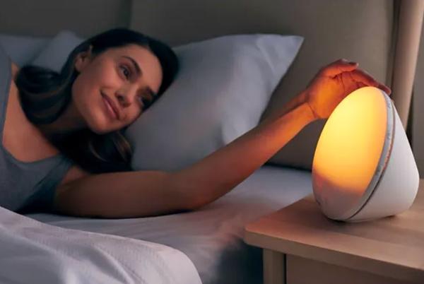 a woman laying in bed with a light on next to her