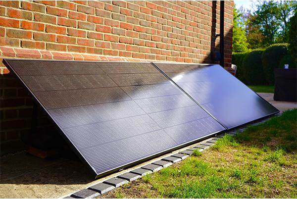 a double plug in solar panel is sitting on the ground next to a brick building