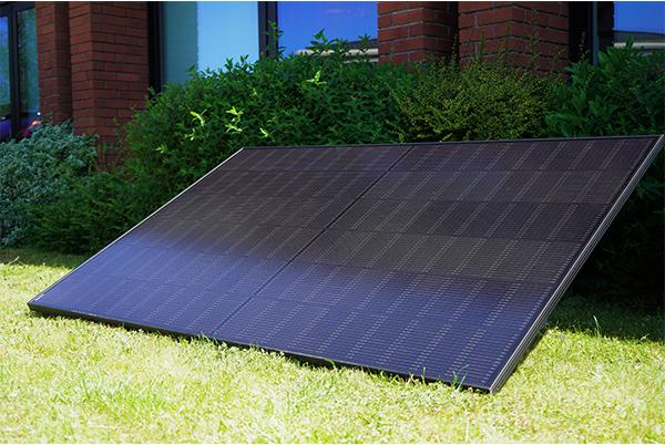 a single plug in solar panel sitting on the grass next to a building