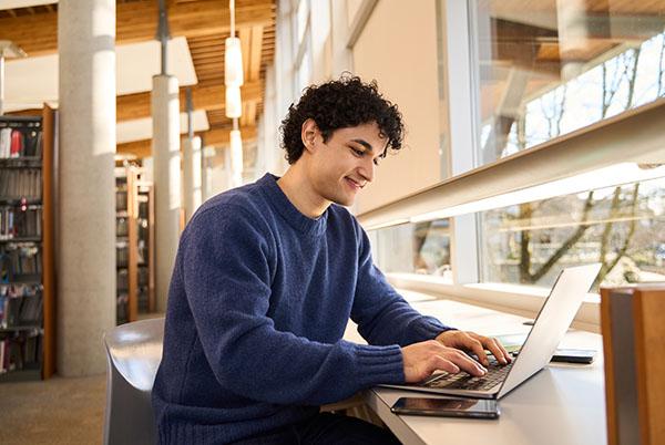 a man sitting at a table with a laptop and a book